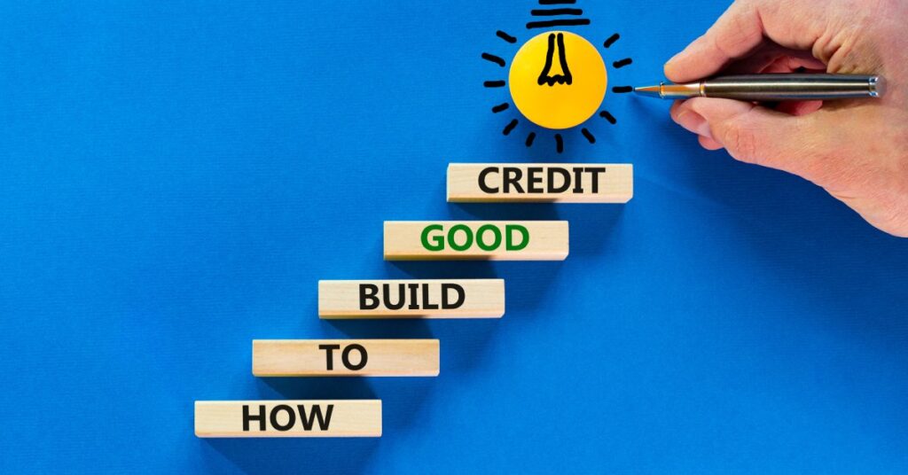 Building blocks form a staircase to a lightbulb with a hand drawing lines. The stairs read "How to Build Good Credit."
