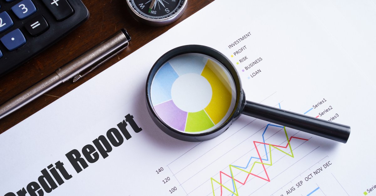 A magnifying glass resting on a document with various bar graphs and data on it. The document is titled "Credit Report."