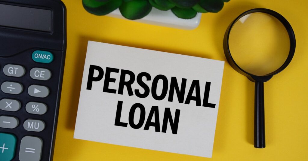 A stack of documents that reads "Personal Loan" lying next to a calculator and magnifying glass on a yellow surface.